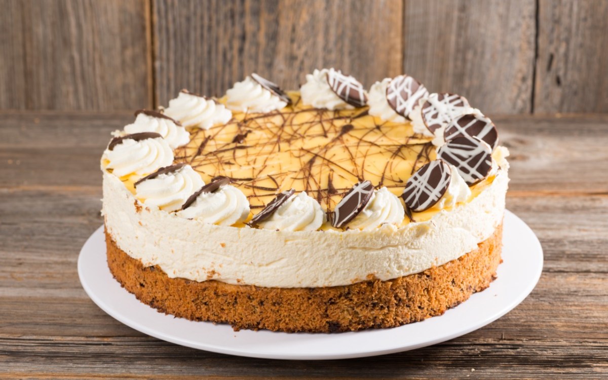 Eine EierlikÃ¶rtorte mit Schokoladenverzierung auf einer flachen Tortenplatte.