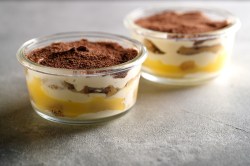 Zwei Gläser mit Eierlikör-Tiramisu auf dunklem Untergrund.