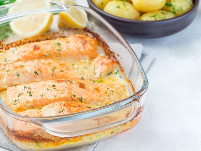 Auflaufform mit Lachs-Sahne-Gratin auf hellem Untergrund