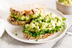 Avocado-Eiersalat auf zwei Broten, die auf einem Teller liegen.