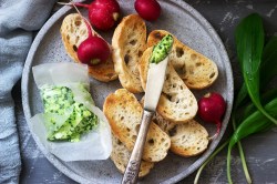 Ein Teller mit gerösteten Brotscheiben, Radieschen und Bärlauchbutter