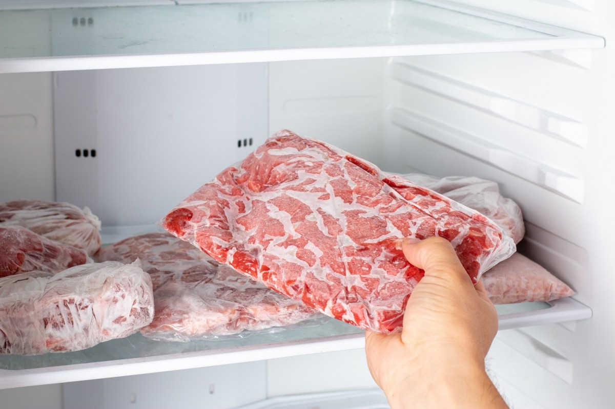 Hackfleisch einfrieren: eine Hand legt eine Packung Hackfleisch ins Gefrierfach