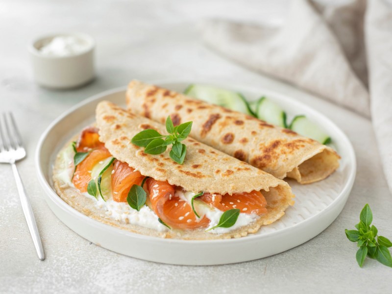 Haferflocken-Pfannkuchen belegt mit Lachs und Frischkäse auf einem Teller.