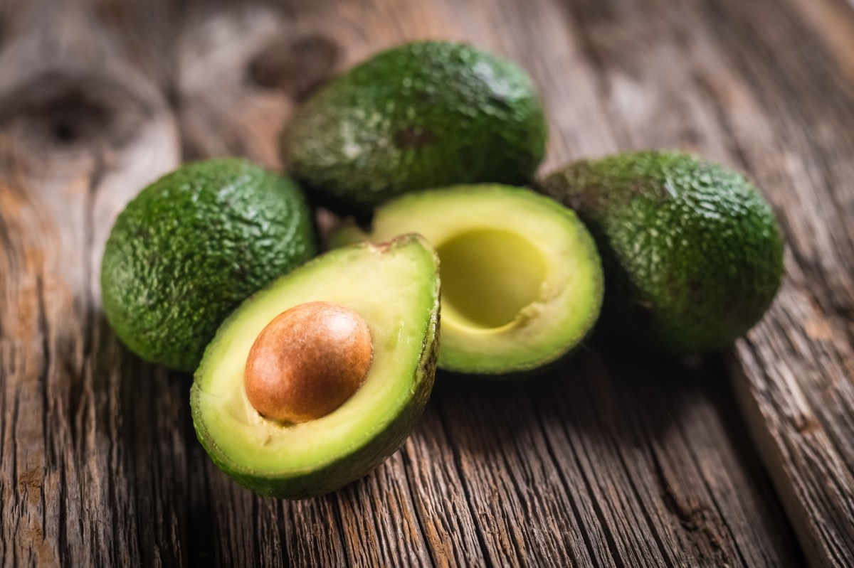 Ist Avocado gesund? Mehrere Avocados liegen auf einem Tisch, davon eine aufgeschnitten