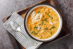 Italienische Pastina-Suppe mit Hühnchen auf einem Tablett.