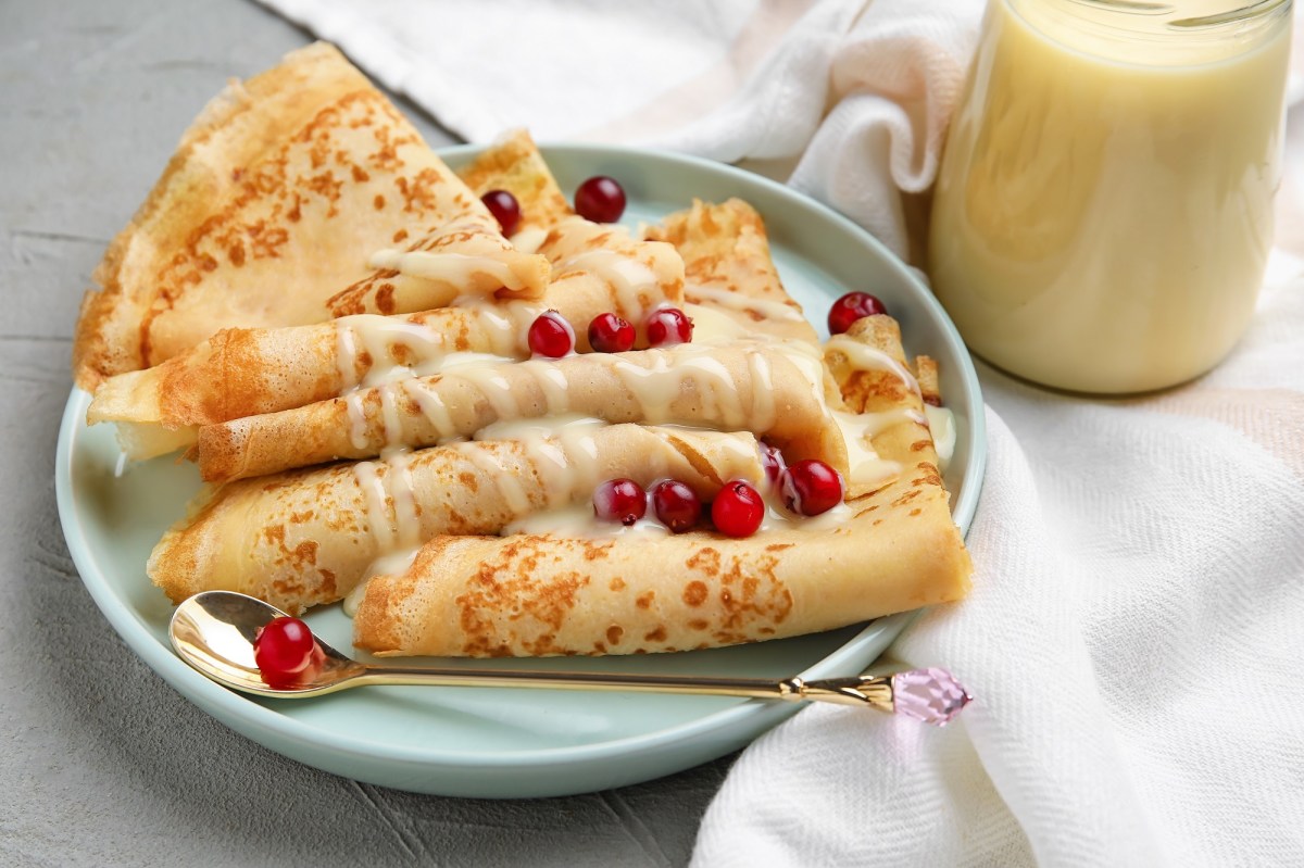 Kondensmilch-Pfannkuchen auf einem Teller, mit Johannisbeeren dekoriert.