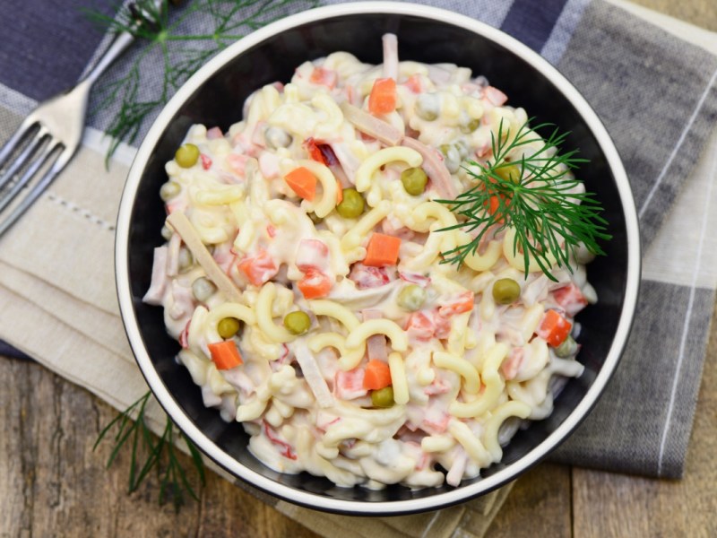 Eine Schüssel mit Nudelsalat mit Mayo in der Draufsicht.