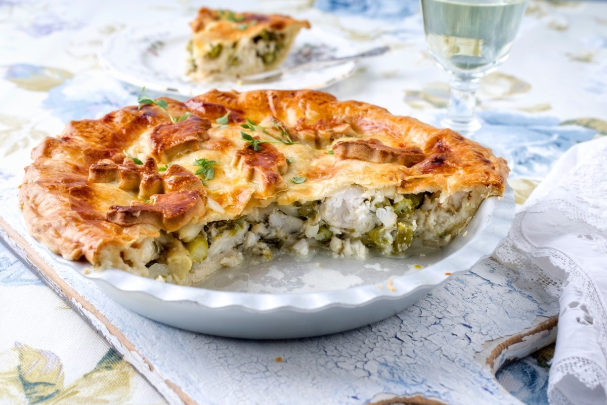 Ein angeschnittene Pastilla mit Fisch und grünem Spargel auf einem Teller.