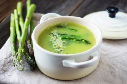 Kleiner Topf mit grüne Spargel Gazpacho und einem Bund Spargel daneben