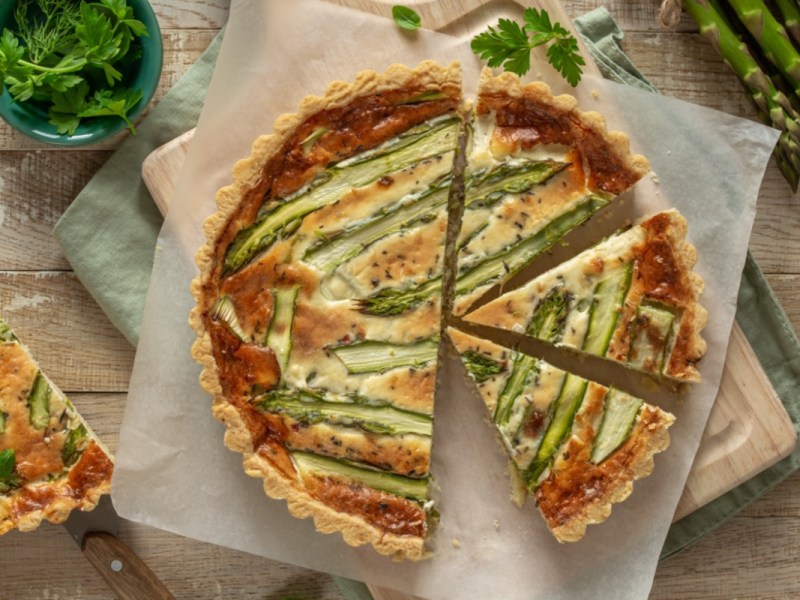 Eine Spargel-Quiche in der Draufsicht, aus der mehrere Stücke geschnitten wurden.