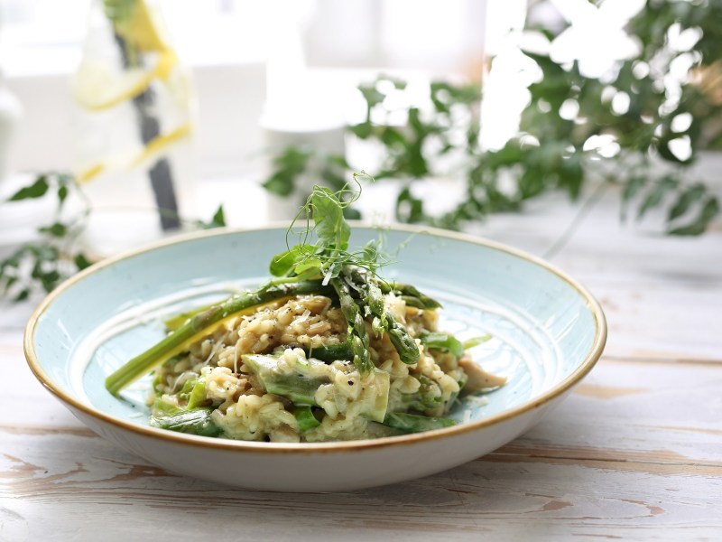 Spargelrisotto mit Spinat und Erbsen, garniert mit Microgreens.