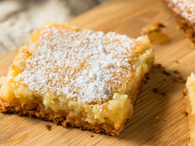 Ein Stück vom St. Louis Gooey Butter Cake auf einem Holzbrett.