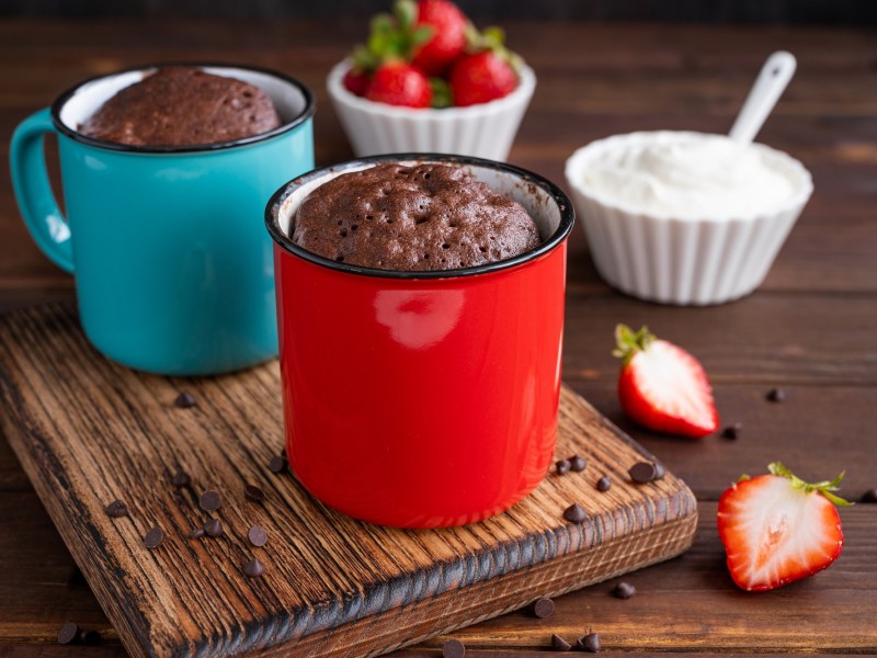 Zwei Tassen-Brownie auf einem Tisch, dekoriert mit Erdbeeren.