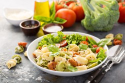 Tortellini-Salat mit Tomaten und Basilikum auf einem Teller.