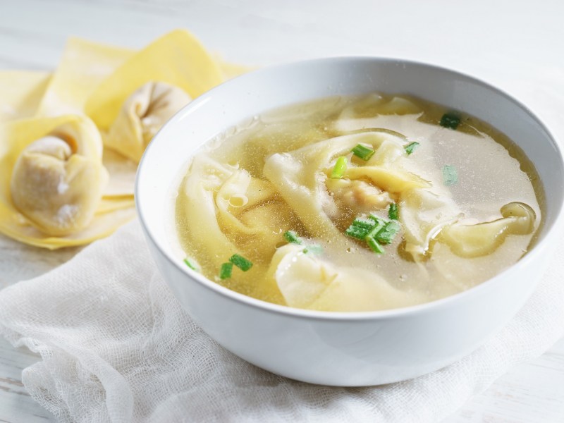 Wan-Tan-Suppe mit Frühlingszwiebeln garniert.