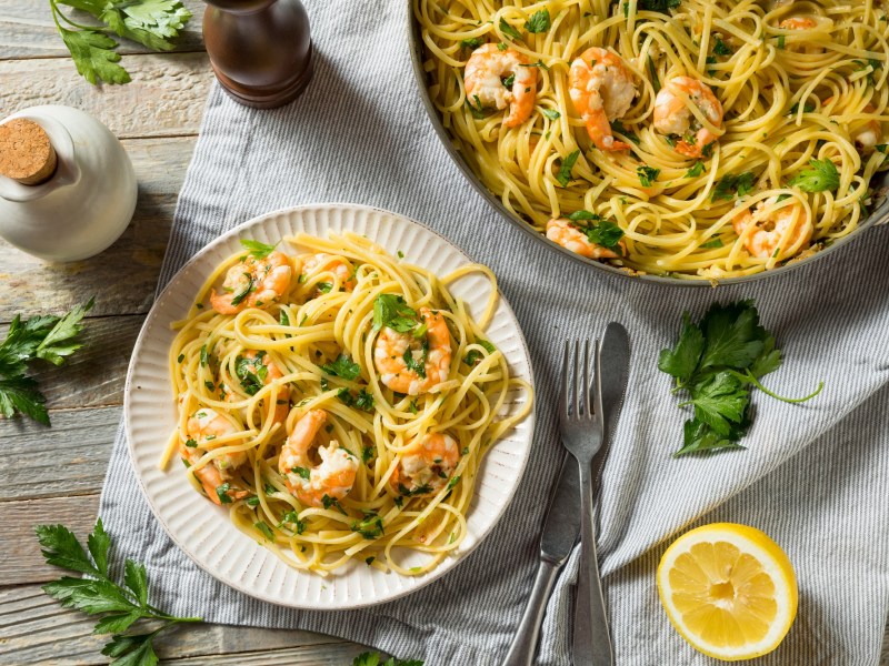 Zitronen-Spaghetti mit Garnelen und Petersilie dekoriert auf einem Teller.