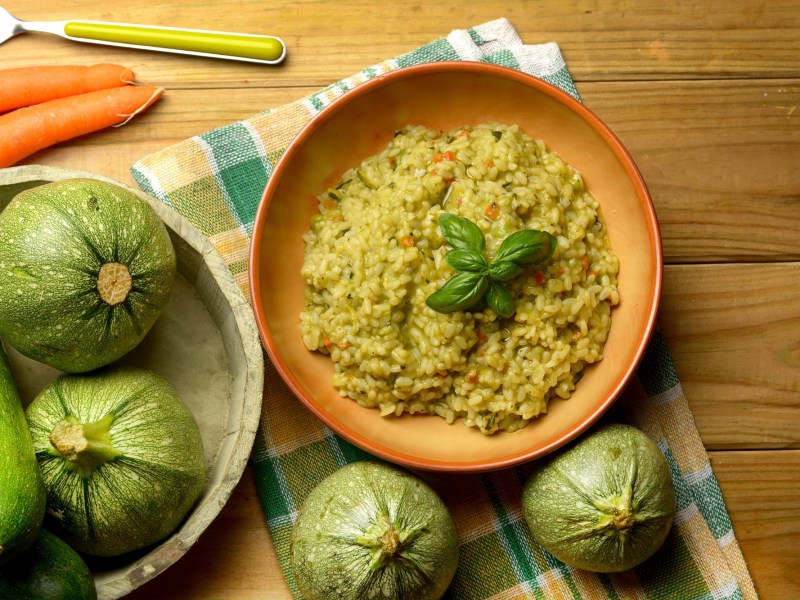 Ein Teller Zucchini-Risotto auf einem dekorierten Tisch.