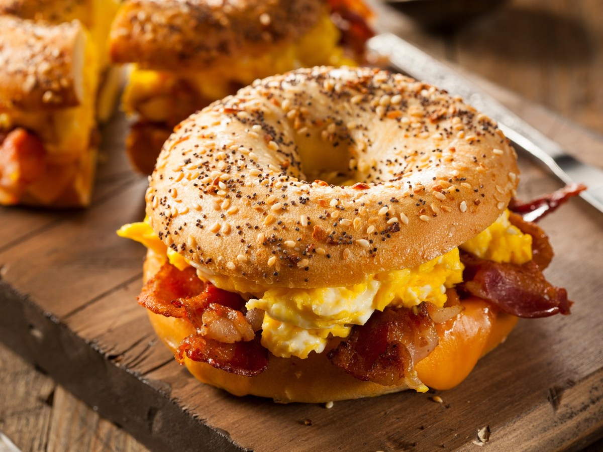 Bagel mit Rührei und Bacon auf einem Brett