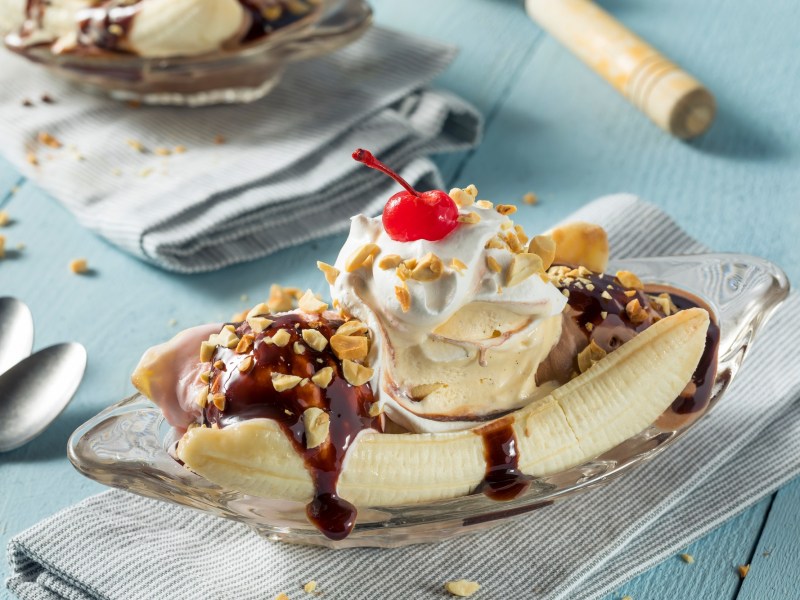 Banana Split auf einem Glasteller auf einer blauen Tischdecke