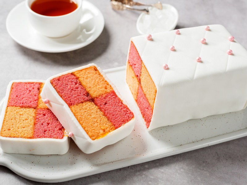 Battenberg-Kuchen mit Schachbrettmuster und eine Tasse Tee.