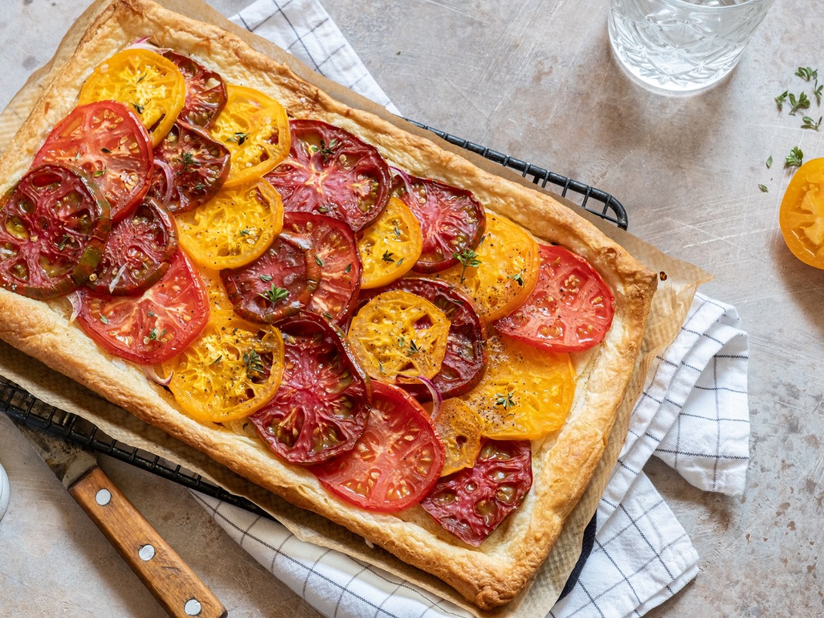 Blätterteig-Tarte mit Tomaten auf einem Kuchengitter, das auf einem Geschirrtuch liegt.