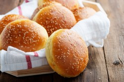 Burgerbrötchen selber machen: Mehrere selbstgemachte Burgerbrötchen in einem Korb, der mit einem Tuch ausgeschlagen ist.