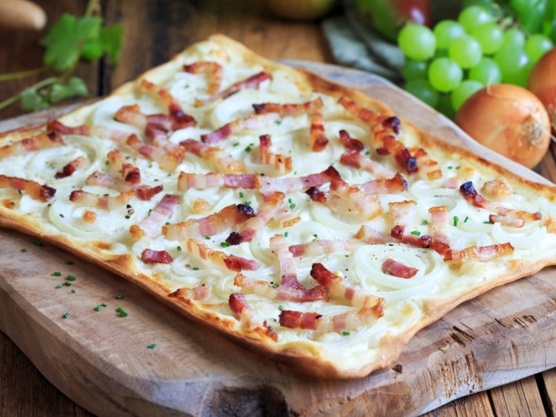 Ein Elsässer Flammkuchen auf einem Holzbrett.