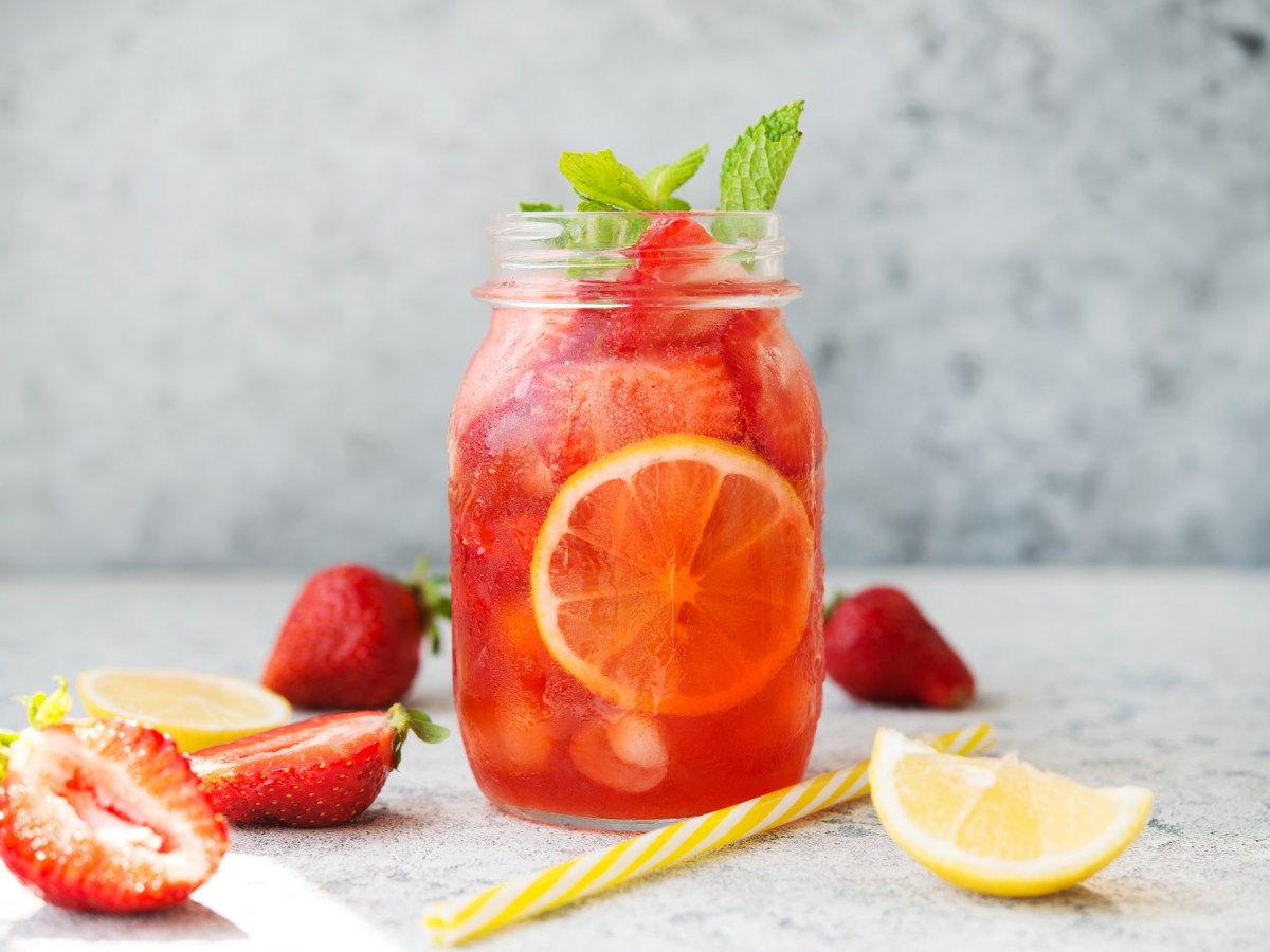 Glas mit Erdbeereistee und Erdbeeren daneben