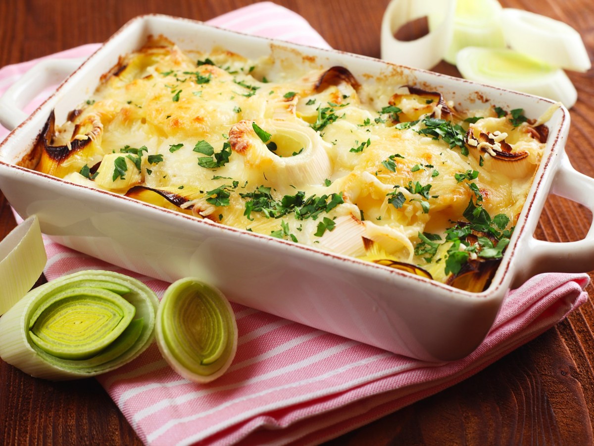 Auflaufform mit Kartoffel-Lauch-Gratin mit Lauch daneben