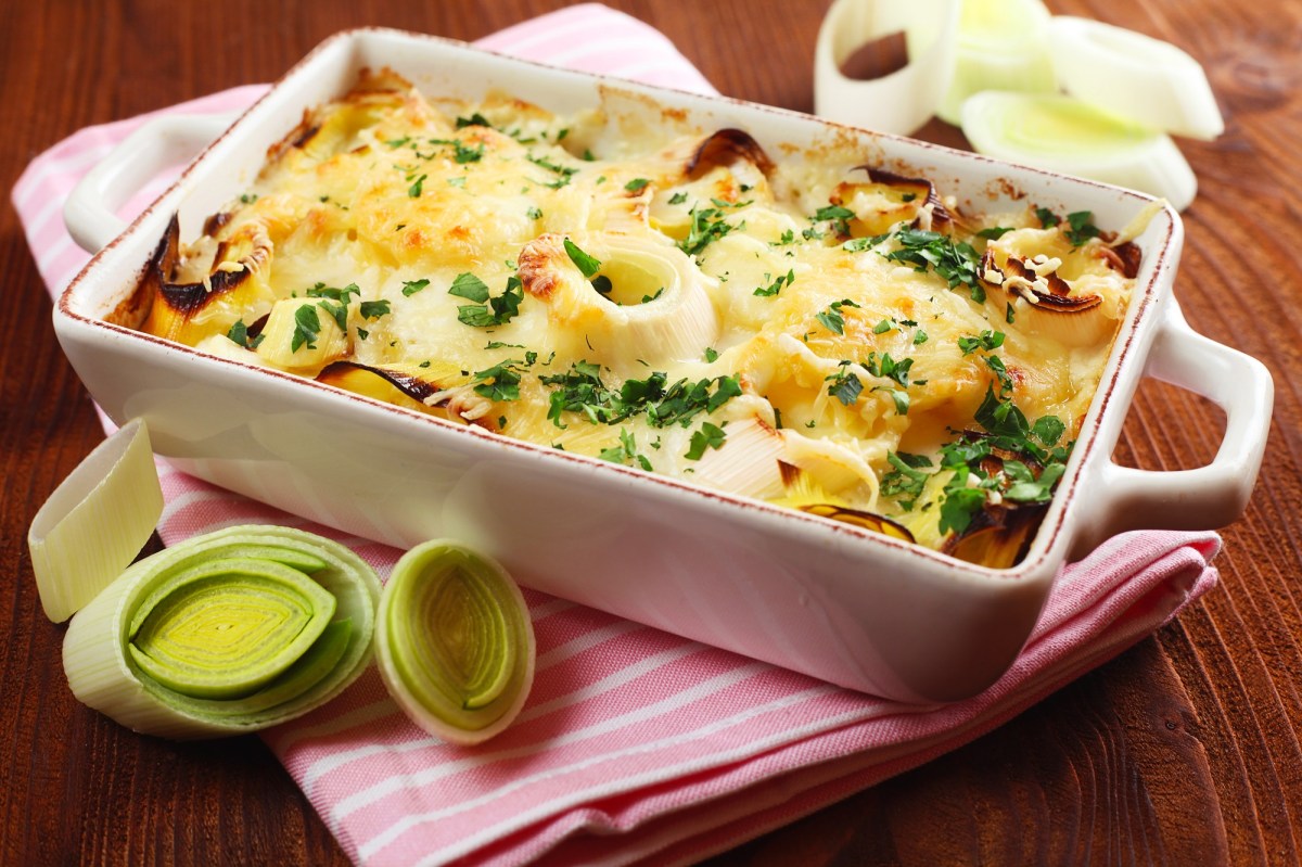 Auflaufform mit Kartoffel-Lauch-Gratin mit Lauch daneben