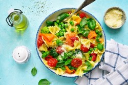 Teller mit Pasta Primavera auf blauem Untergrund