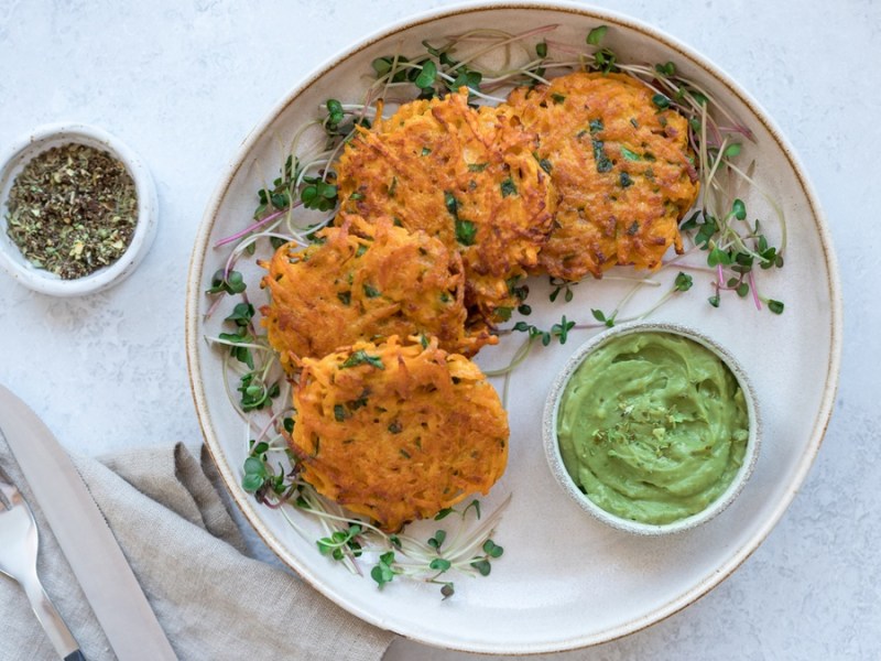 Süßkartoffel-Puffer auf weißem Teller mit grünem Avocado-Dip