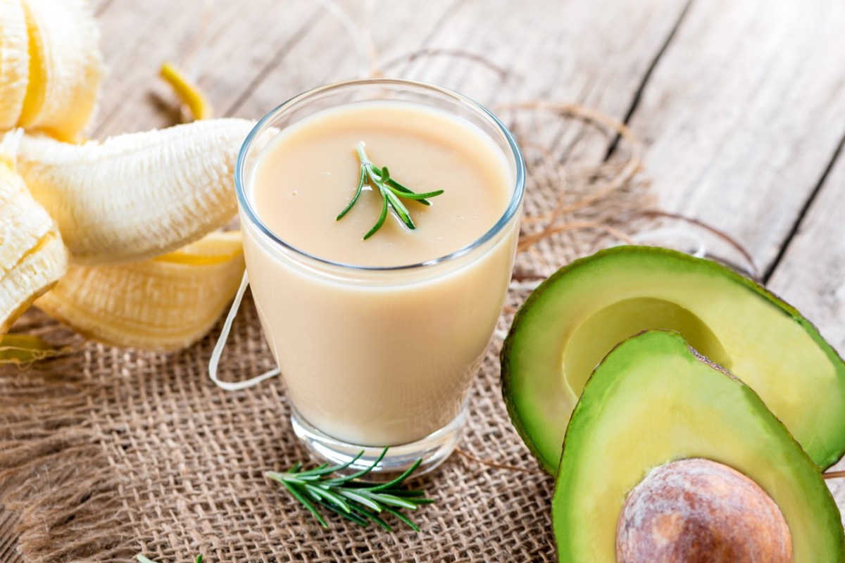 Ein Avocado-Bananen-Smoothie im Glas. Drumherum Zutaten.