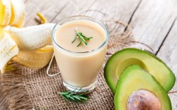 Ein Avocado-Bananen-Smoothie im Glas. Drumherum Zutaten.