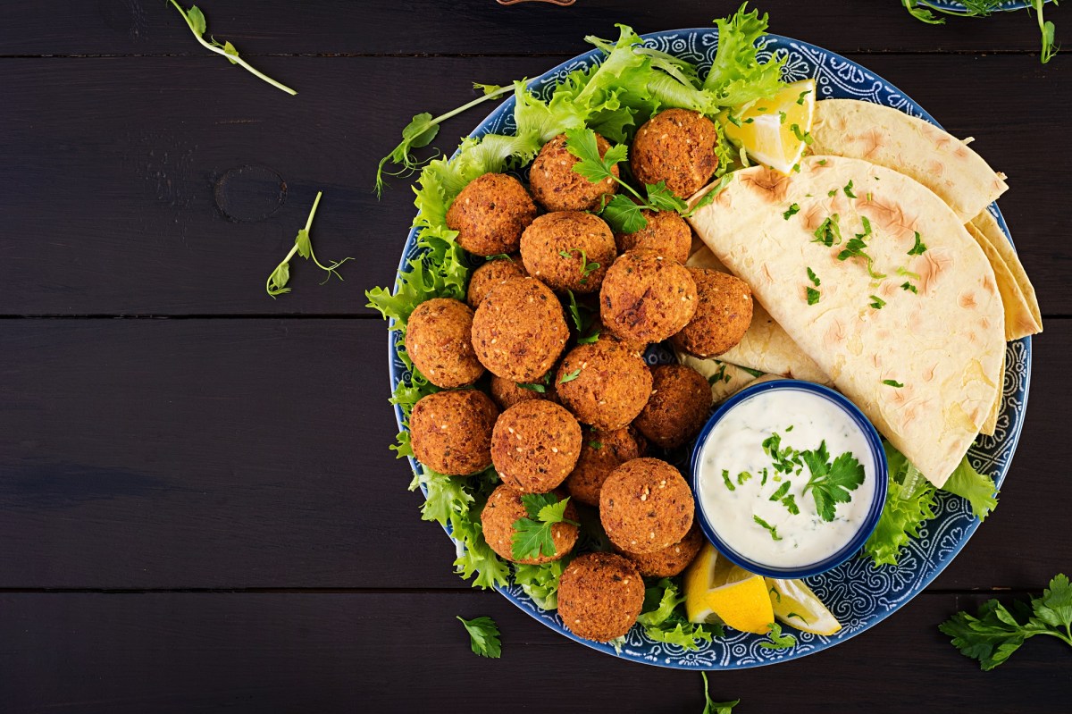 Falafel selber machen: Falafelbällchen auf einem Teller. Dazu Salat, Fladenbrot und Joghurtdip