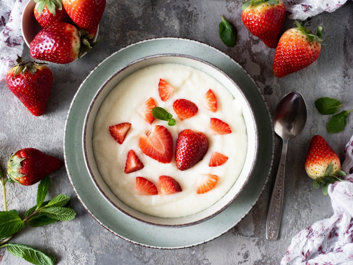 Schüssel mit Grießbrei mit Erdbeeren, frische Erdbeeren daneben