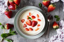 Schüssel mit Grießbrei mit Erdbeeren, frische Erdbeeren daneben