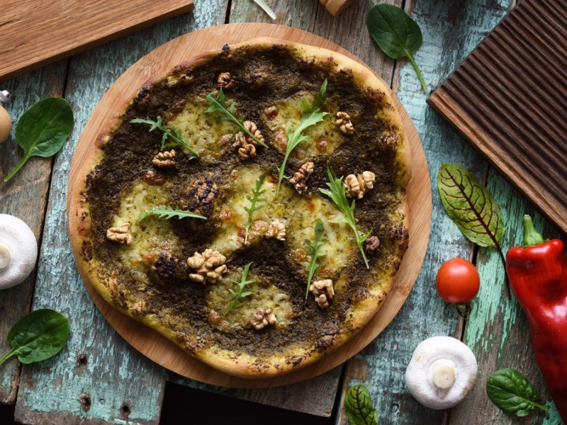 Pizza mit grünem Pesto und Walnüssen.