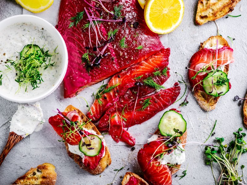 Tisch mit gebeiztem Lachs mit Roter Bete, Zitrone, Brot und Aufstrich