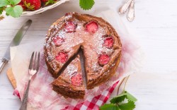 Ein Schoko-Käsekuchen mit Erdbeeren in der Draufsicht. Ein Stück wurde herausgeschnitten.