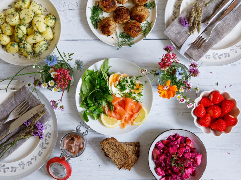 festlich gedeckter Mittsommertisch mit Erdbeeren, Lachs und Dillkartoffeln