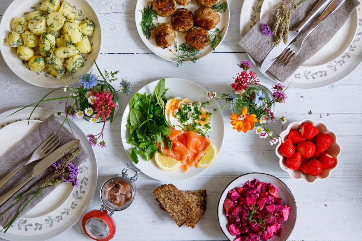 festlich gedeckter Mittsommertisch mit Erdbeeren, Lachs und Dillkartoffeln