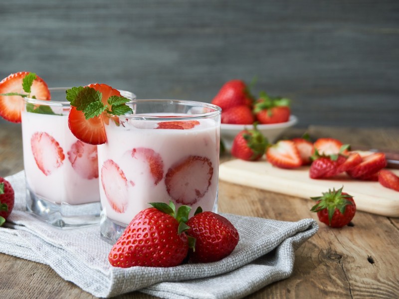 Zwei Gläser Yogurette-Dessert auf einem Tisch mit Erdbeeren