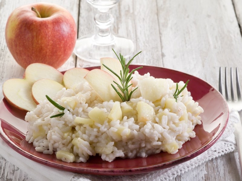 Apfel-Parmesan-Risotto in heller Schale mit einem Apfel.