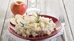 Apfel-Parmesan-Risotto in heller Schale mit einem Apfel.