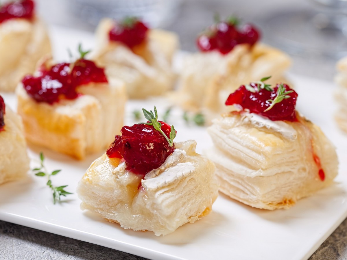 Blätterteig-Häppchen mit Camembert auf einem Tablett.