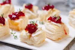 Blätterteig-Häppchen mit Camembert auf einem Tablett.