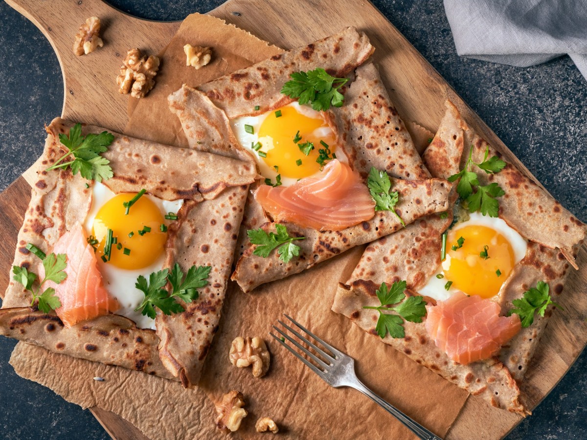 Bretonische Galettes mit Ei und Lachs auf einem Brett.