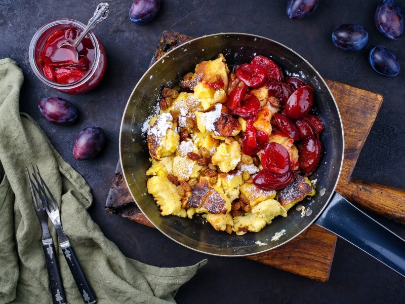 Kaiserschmarrn mit Pflaumenkompott in einer Pfanne.