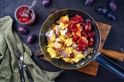 Kaiserschmarrn mit Pflaumenkompott in einer Pfanne.